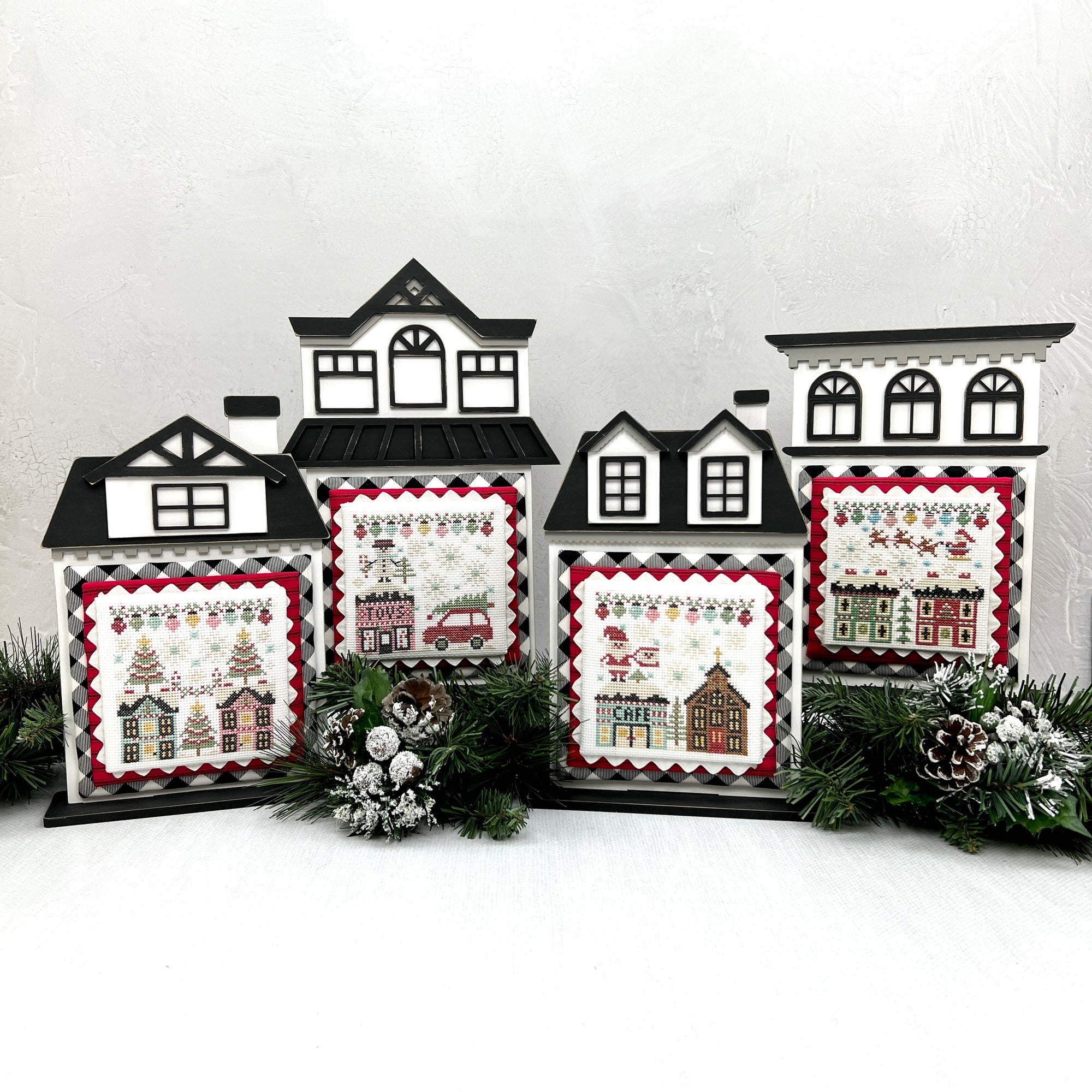 Stitching with the Housewives City Christmas cross stitch displayed on wood city houses