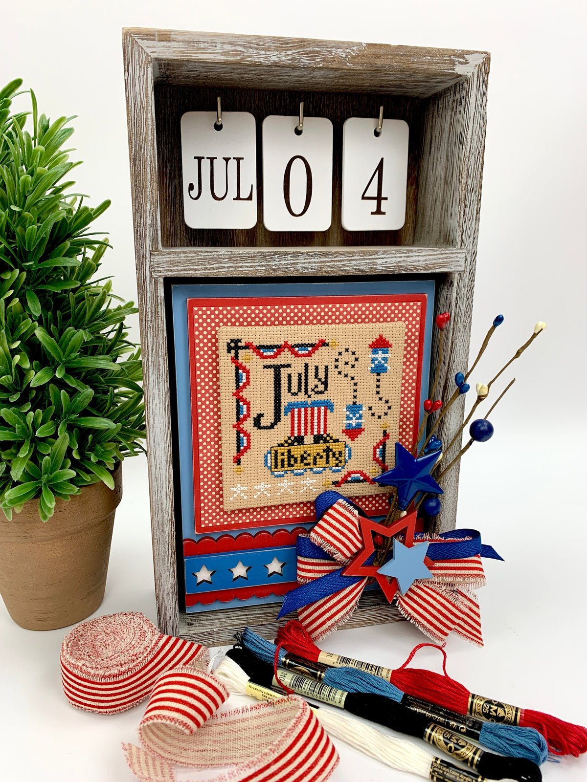 Hands on Design a year of celebrations cross stitch july pattern shown in a wood calendar box. 