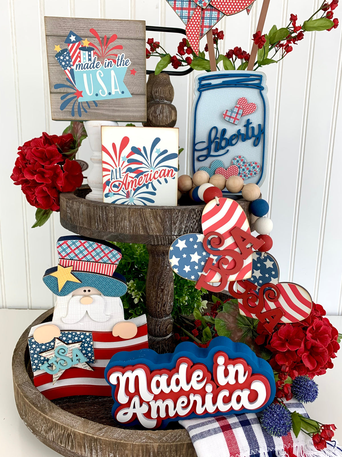 Patriotic or 4th of July tiered tray with a mason jar and other patriotic red, white, and blue wood decor pieces.  close up view