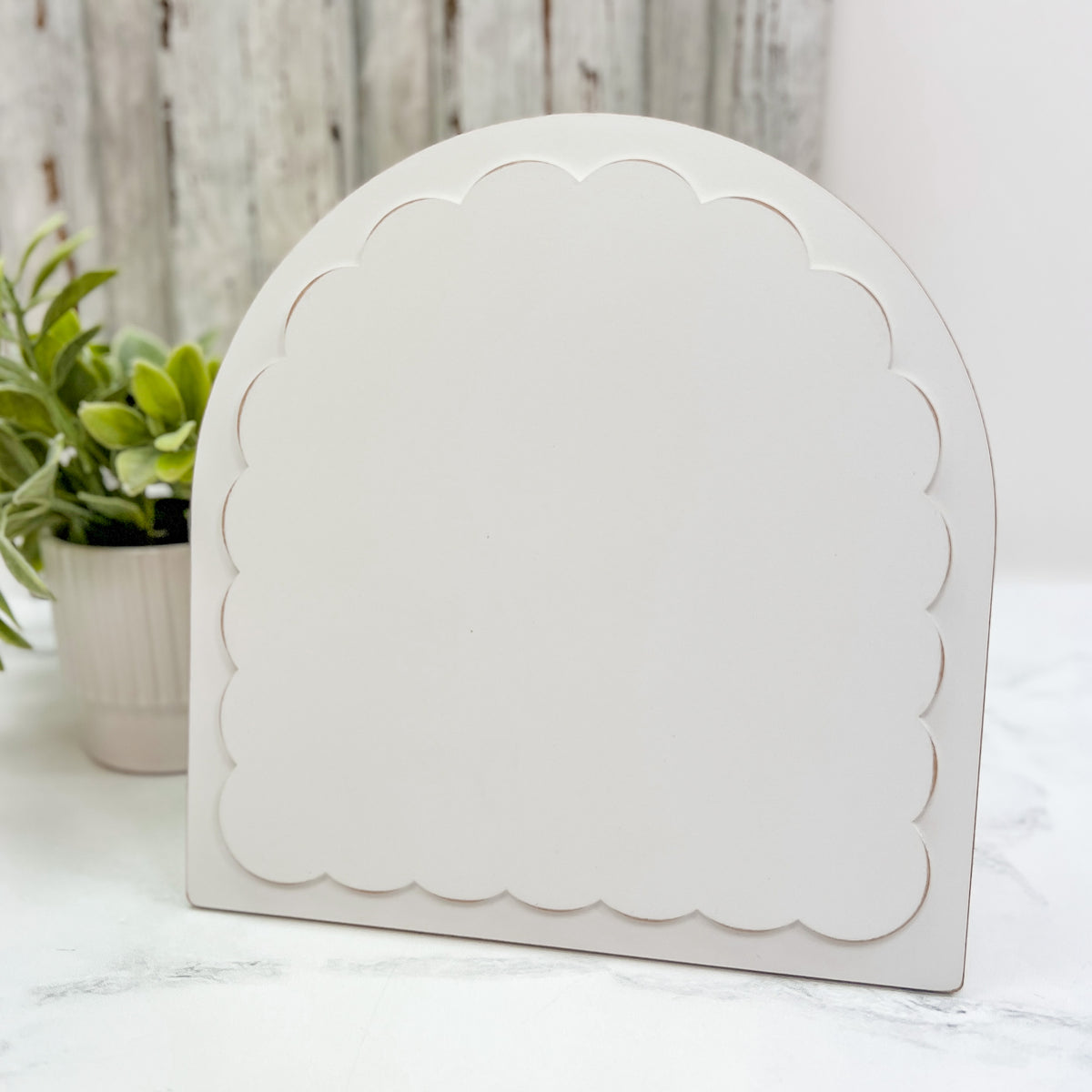Pre-painted arched scallop embroidery and cross stitch frame with a neutral finish, holding a round floral embroidery hoop and displayed with an easel stand.
