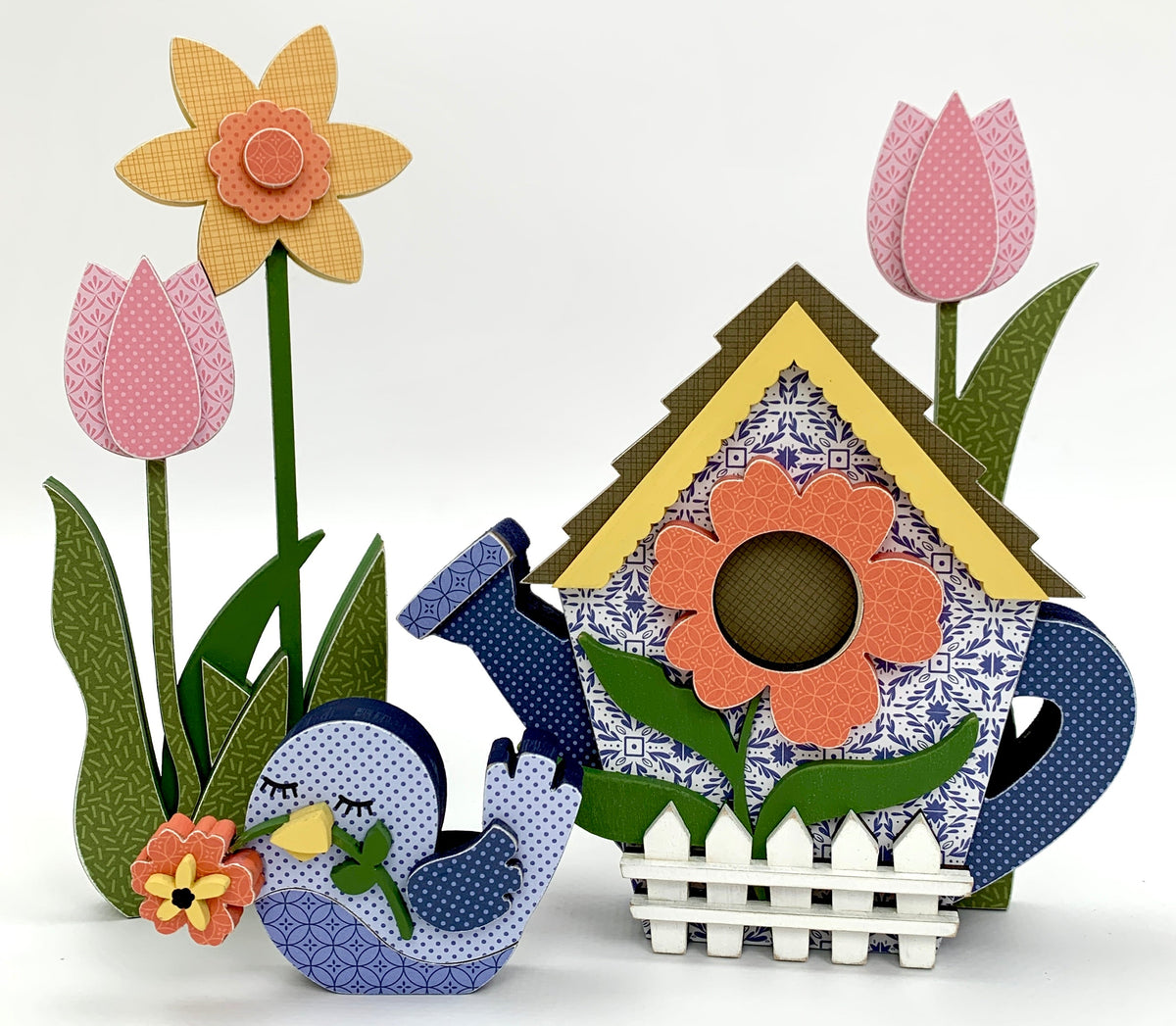 Watering can birdhouse wood decoration with blue bird, pink tulips, and yellow daffodil. 
