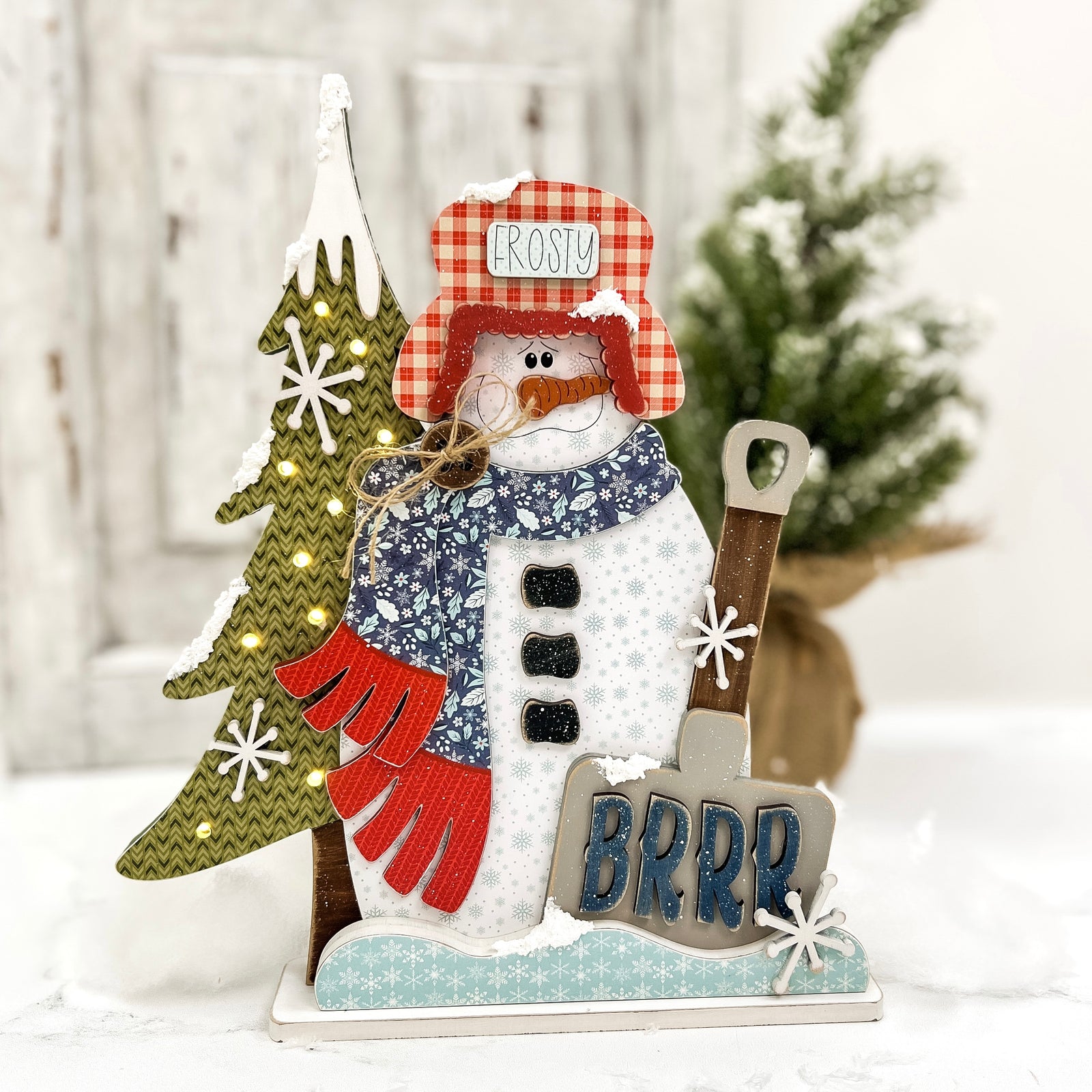 Handcrafted snowman wood decor with BRRR shovel sign and glowing tree lights