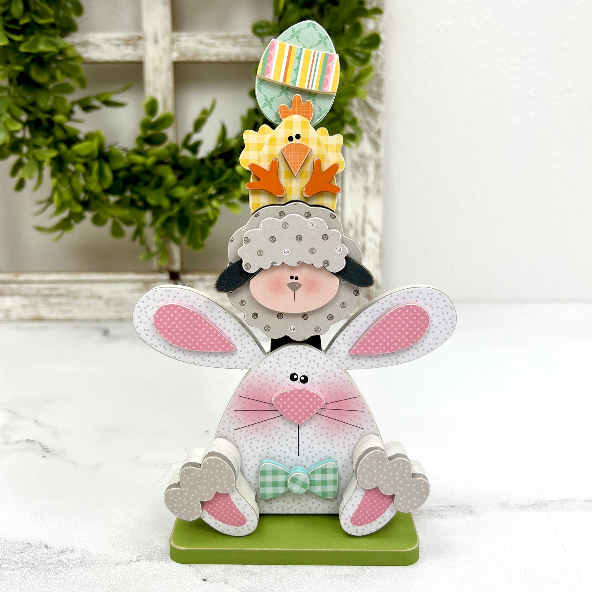 Easter bunny, lamb, chick, and egg stacked on top of each other to create a spring decoration. 