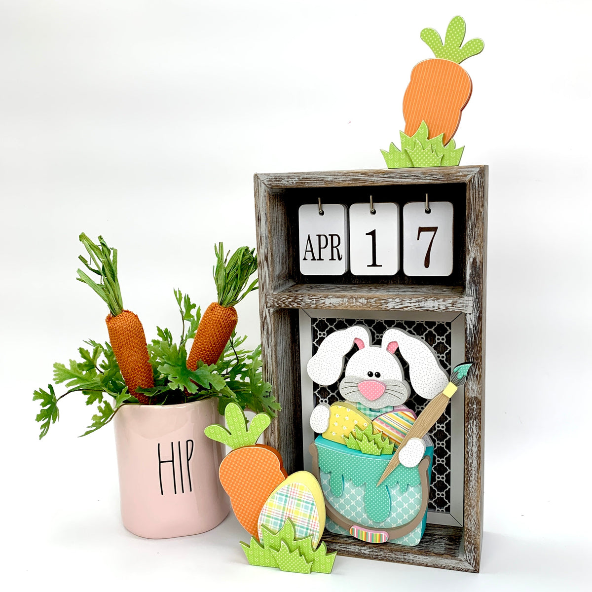 Changing seasonal calendar box with Easter decor; bunny painting eggs and carrots. 