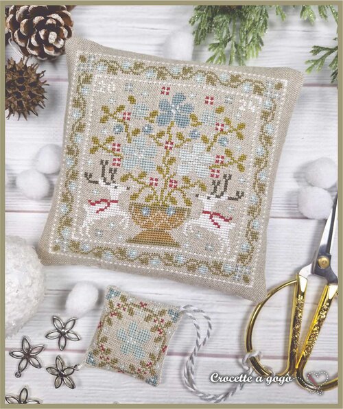 Cross-stitched pillow with winter floral design and reindeer and a scissor fob in a winter floral quilt design