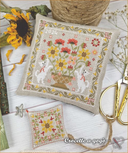 Cross-stitched pillow with a floral design featuring playful cats and a sunflower quilt design scissor fob