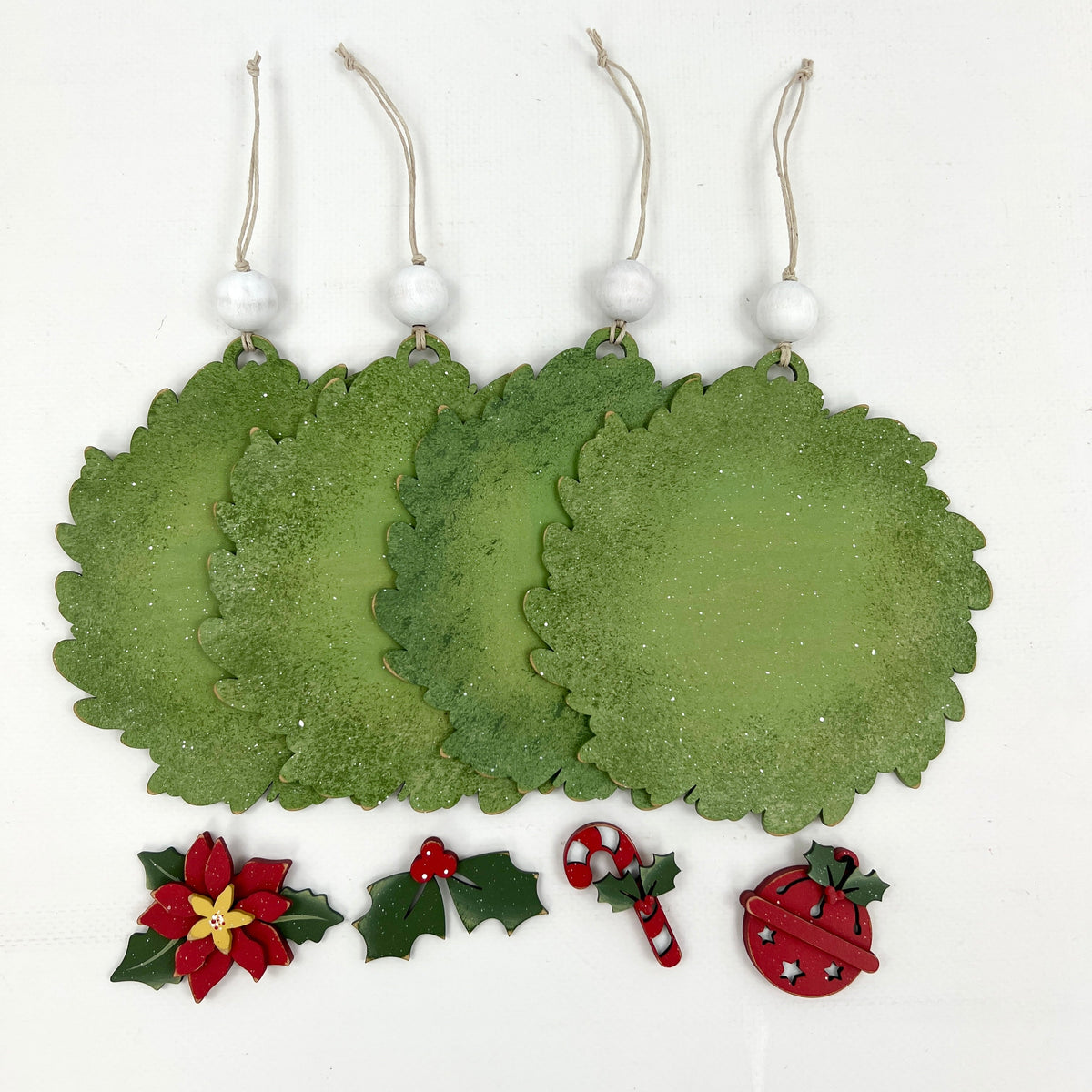 Wood Christmas wreath ornaments for displaying round cross stitch finished pieces with 4 charms; poinsettia, holly leaf, candy cane, and a jingle bell.
