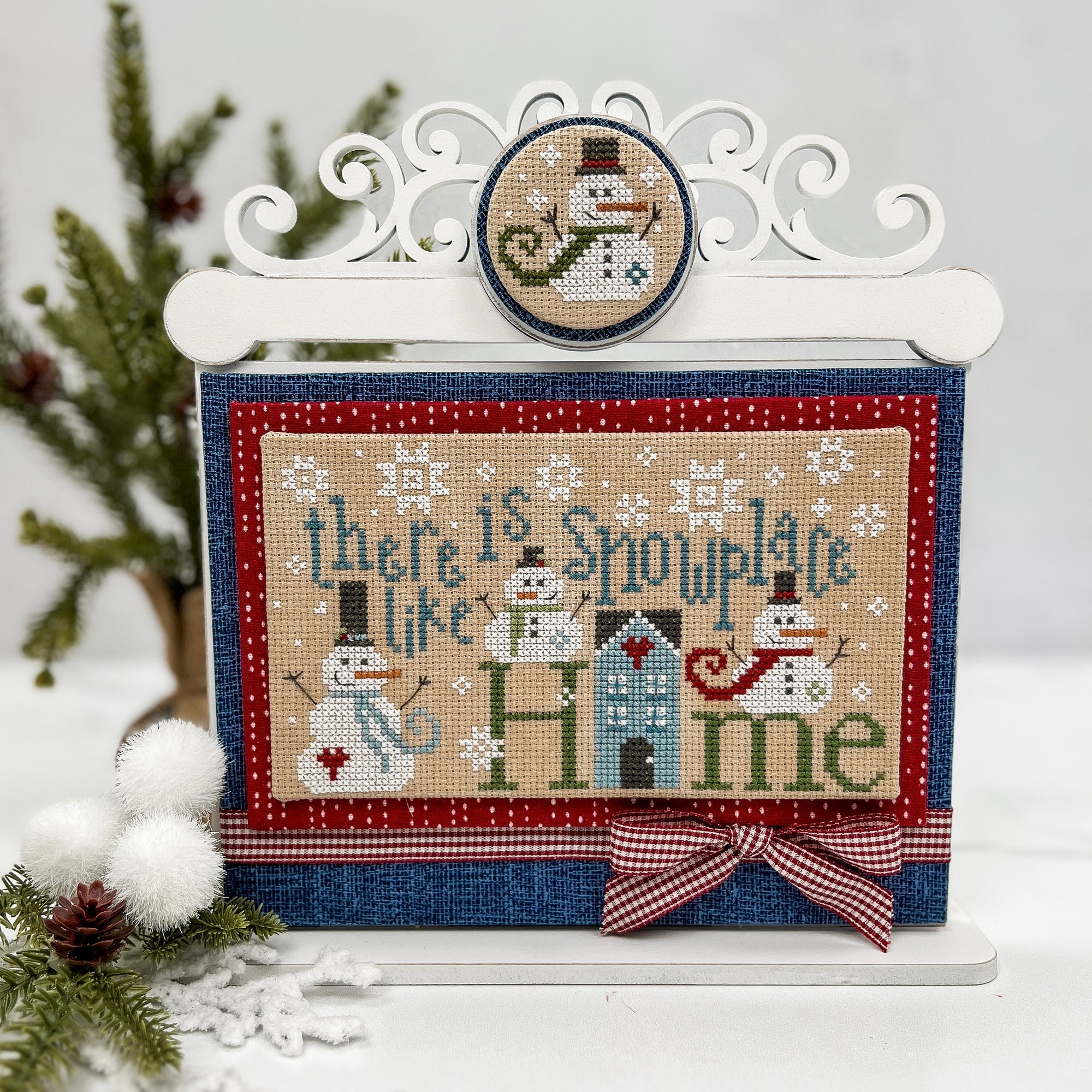 Cross stitch display with a scroll work top with a finished cross stitch Snowplace like home from Primrose Cottage