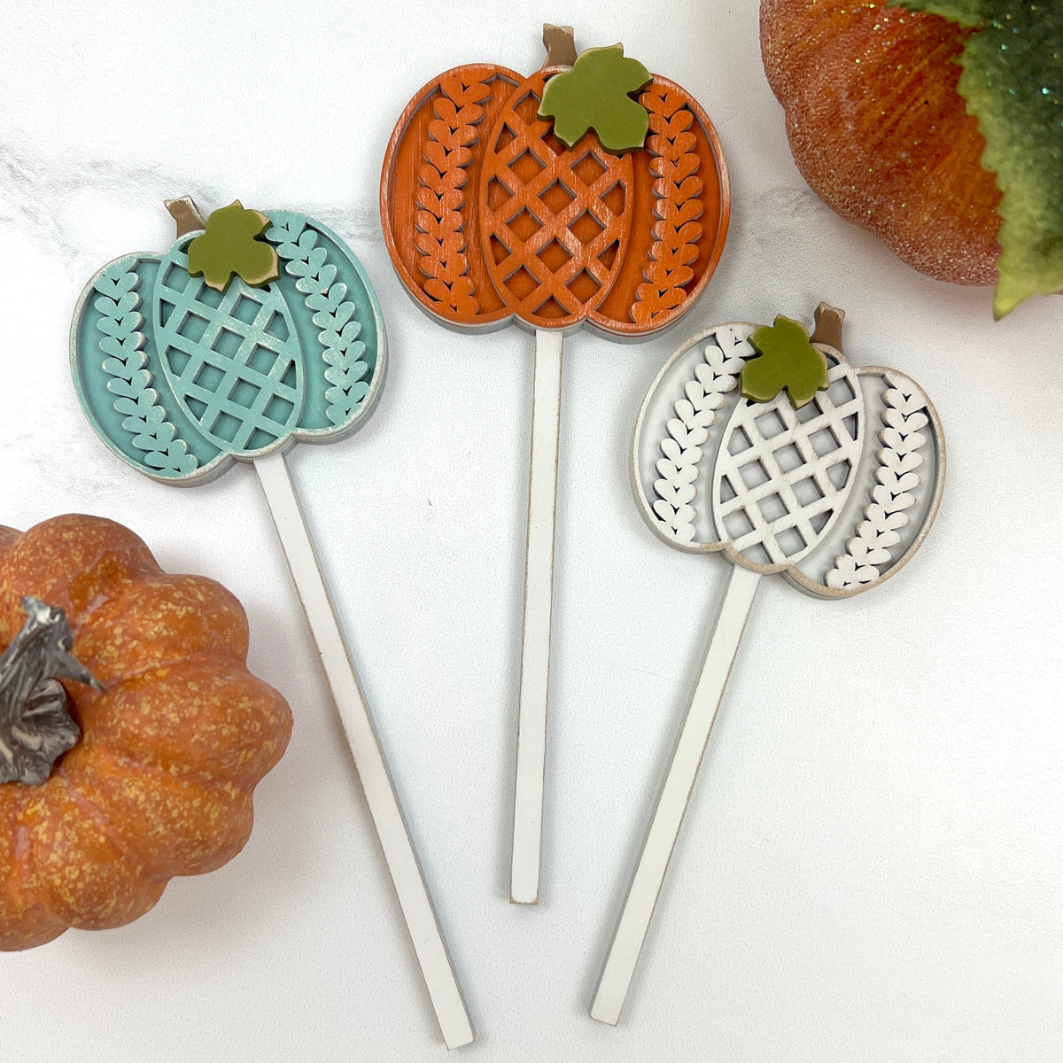 wood sticks with pumpkins with details that resemble sweaters. Wood craft shapes for fall seasonal decorating and DIY crafts.