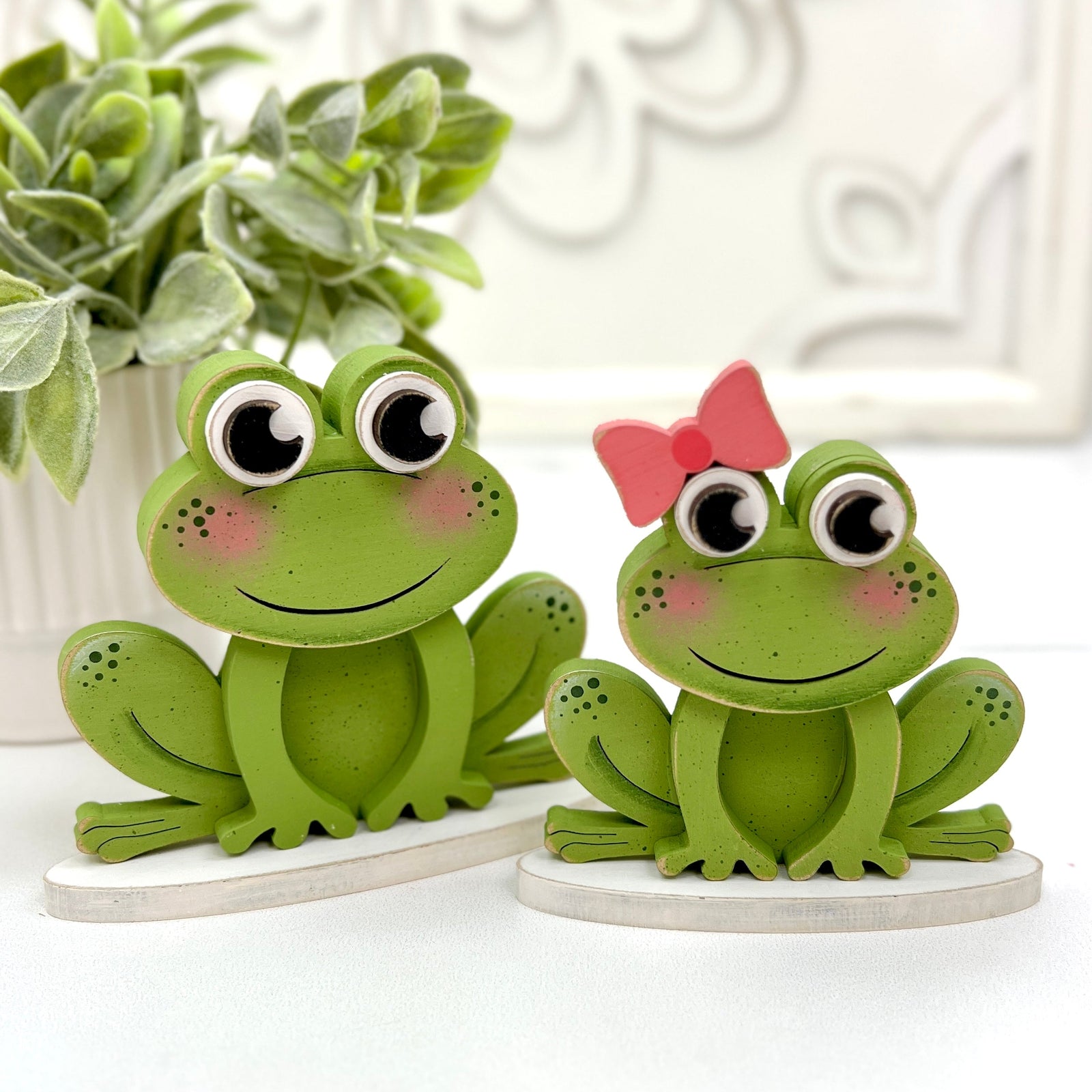 Two cute green wood frogs. Girl frog with pink bow. For styling tiered trays or self sitters