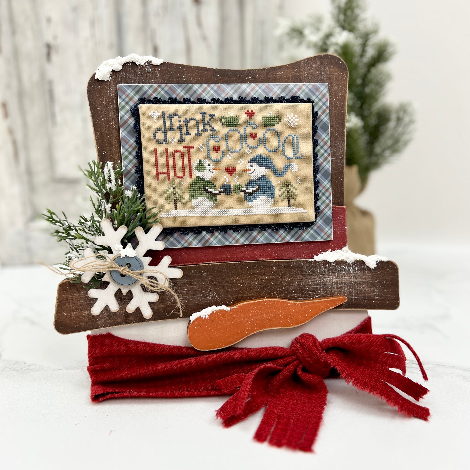 Unfinished wood Frosty’s Top Hat cross stitch display featuring a snowman-themed finished cross stitch, painted and styled for winter décor.