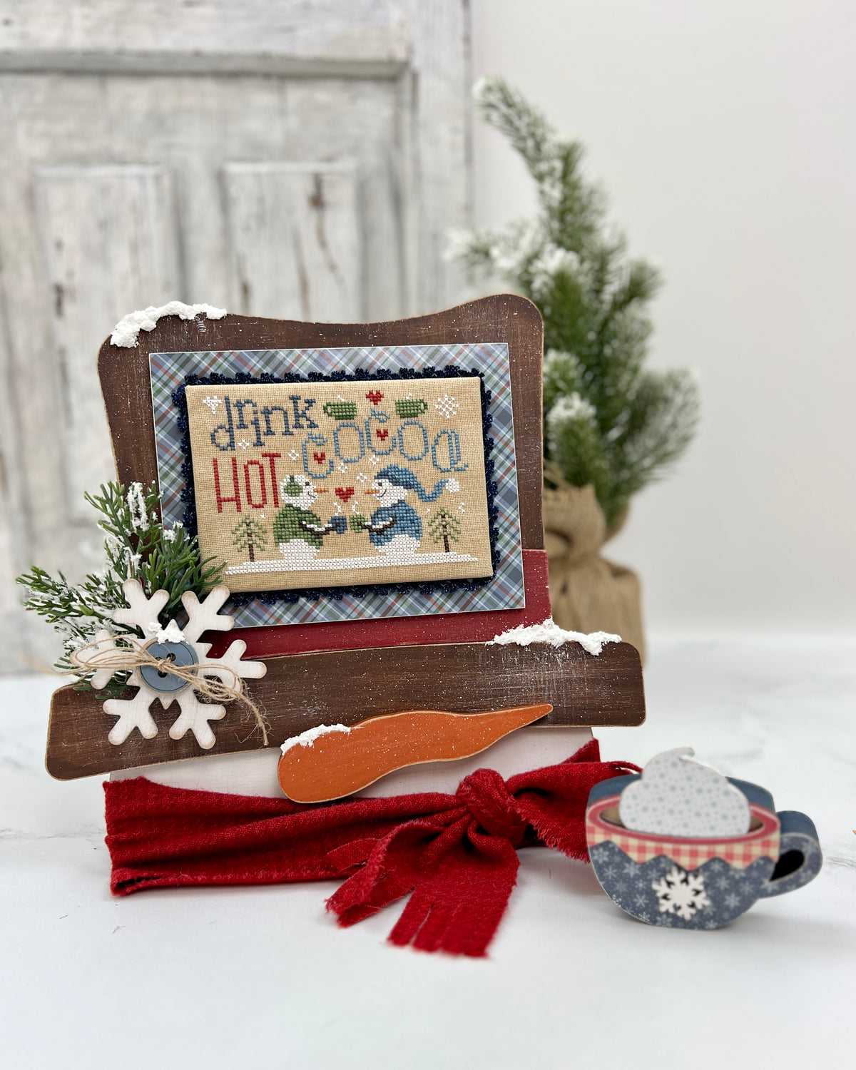 Unfinished wood Frosty’s Top Hat cross stitch display featuring a snowman-themed finished cross stitch, painted and styled for winter décor.
