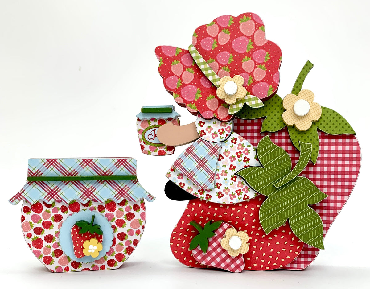 Strawberry shortcake inspired wood decor craft kit with a girl sitting on a strawberry holding a jam jar.