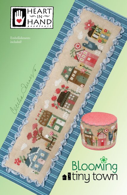 Cross-stitched pattern of a tiny town in full spring bloom featuring colorful houses bursting with spring flowers and a bluebird