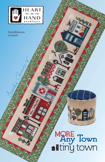 Cross-stitched design of a town scene with a pizza place, movie theater, quilt shop, toy store, chapel and market