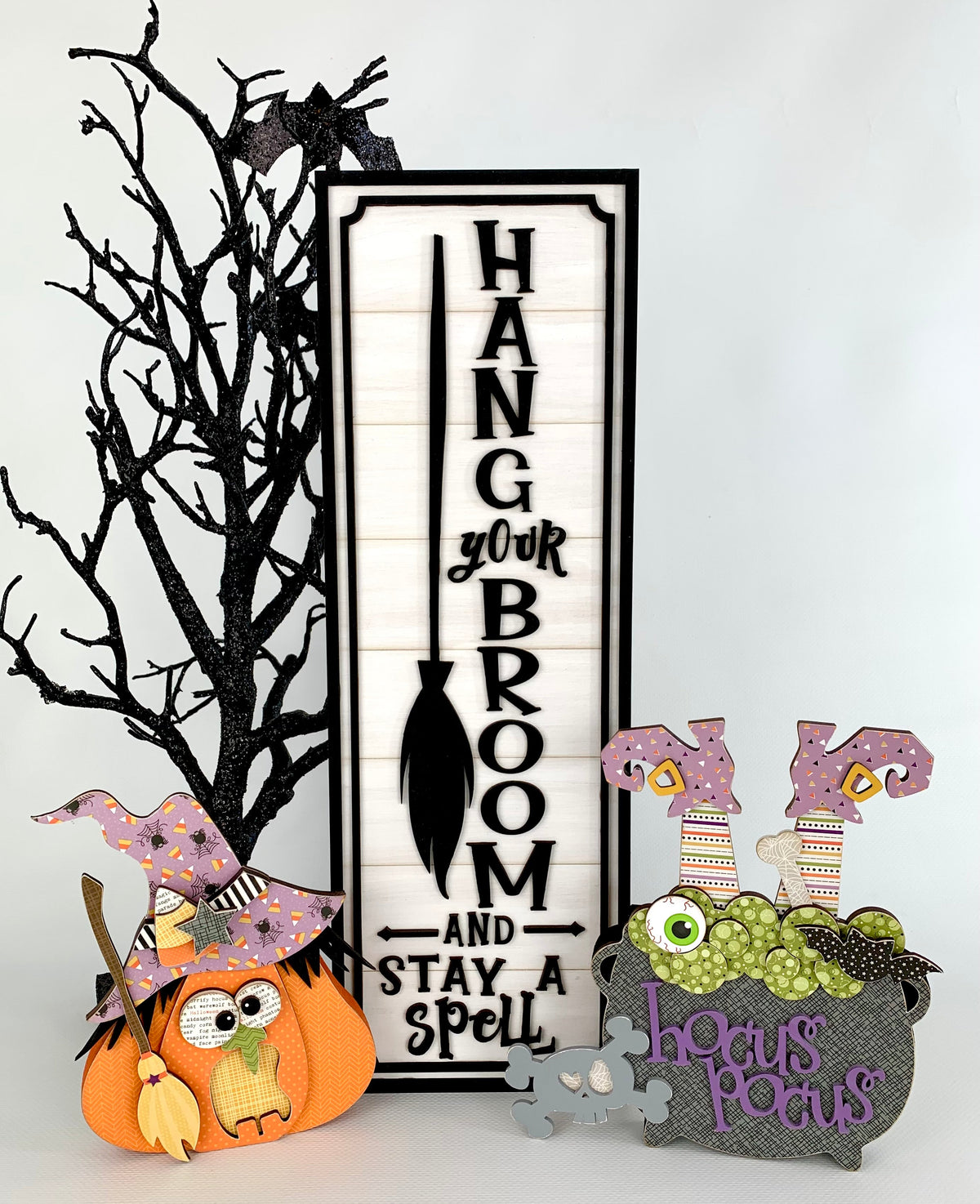 Black and white wood halloween dimensional shiplap sign with a witch pumpkin and hocus pocus witch cauldron with witches feet sticking out.  Wood craft kits for making halloween decorations.