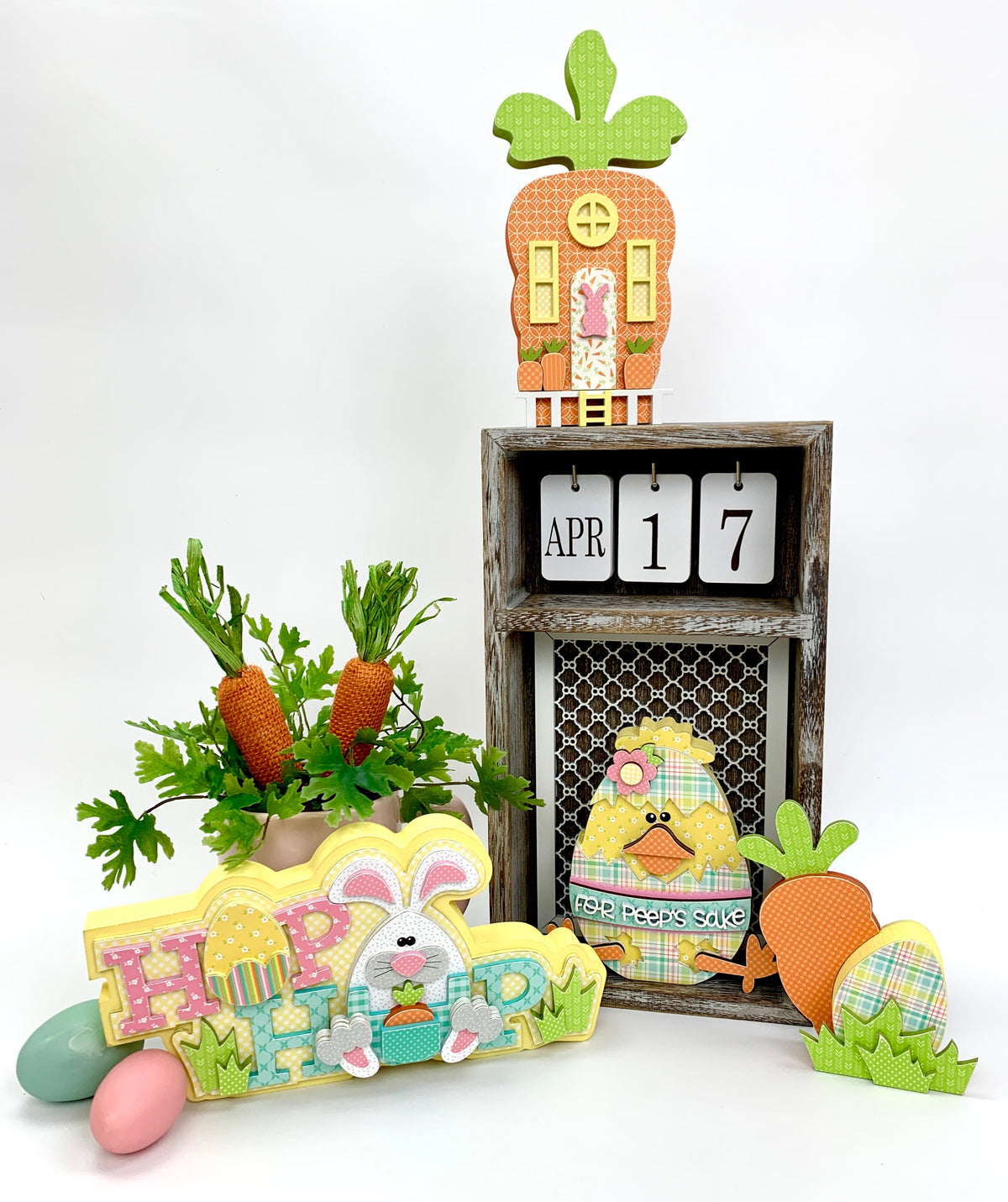 Wood Easter decorations with a bunny, easter chick inside an egg, and a carrot house shown with a calendar box