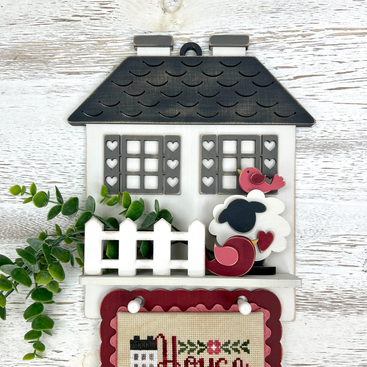 Cottage cross stitch display decorated with tiny chunky sheep and birds on the shelf