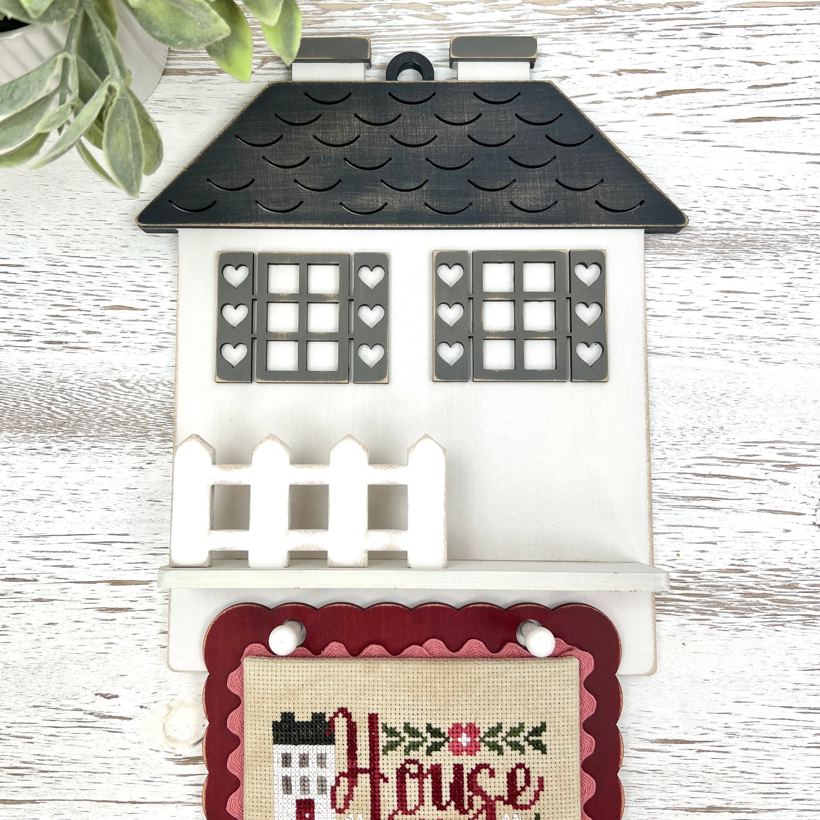 House Rules cottage DIY cross stitch display with heart shutters, picket fence shelf, and hanging pegs