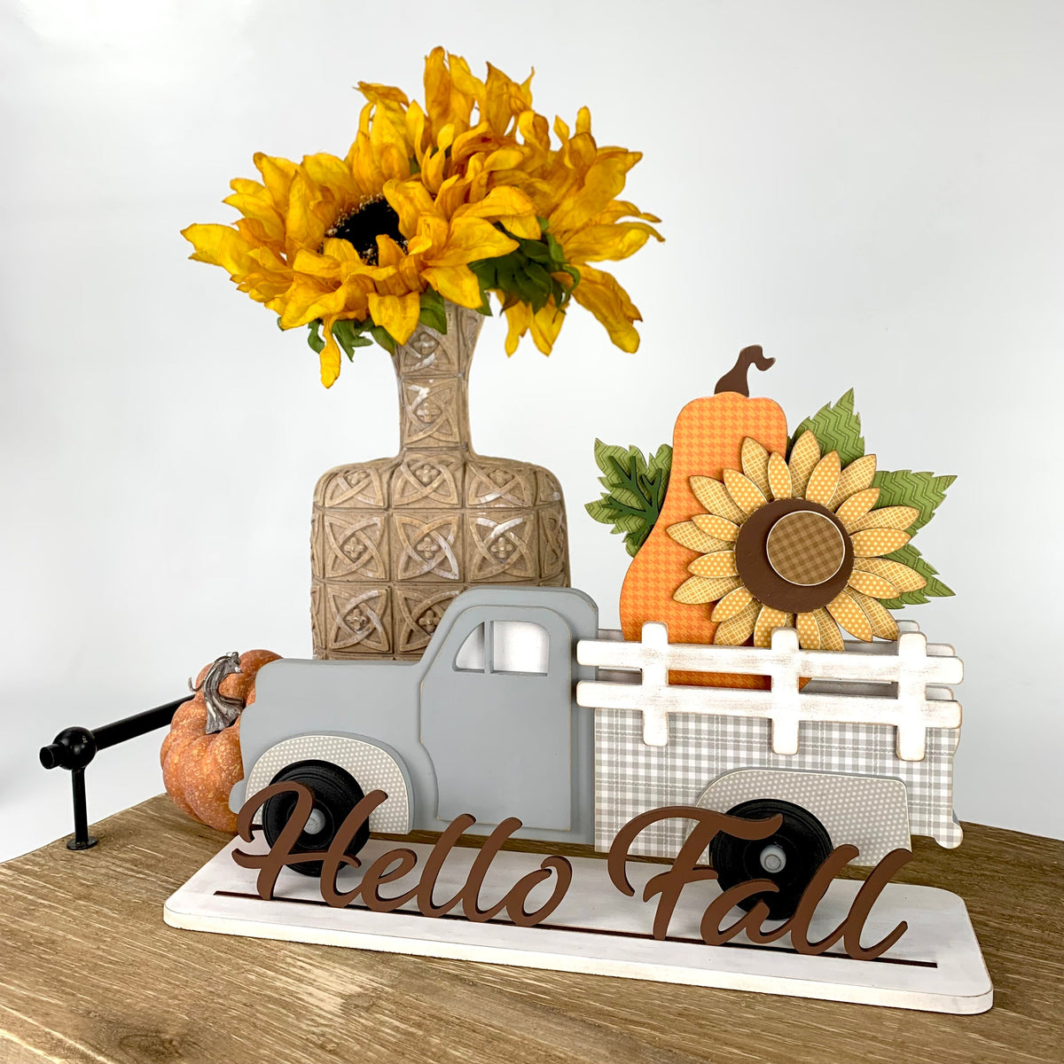 Interchangeable pick up truck with removable inserts to change monthly or seasonally.  Truck shown with a fall sunflower and orange pumpkin. This is a wood decor craft kit shown on a wood tray with sunflowers