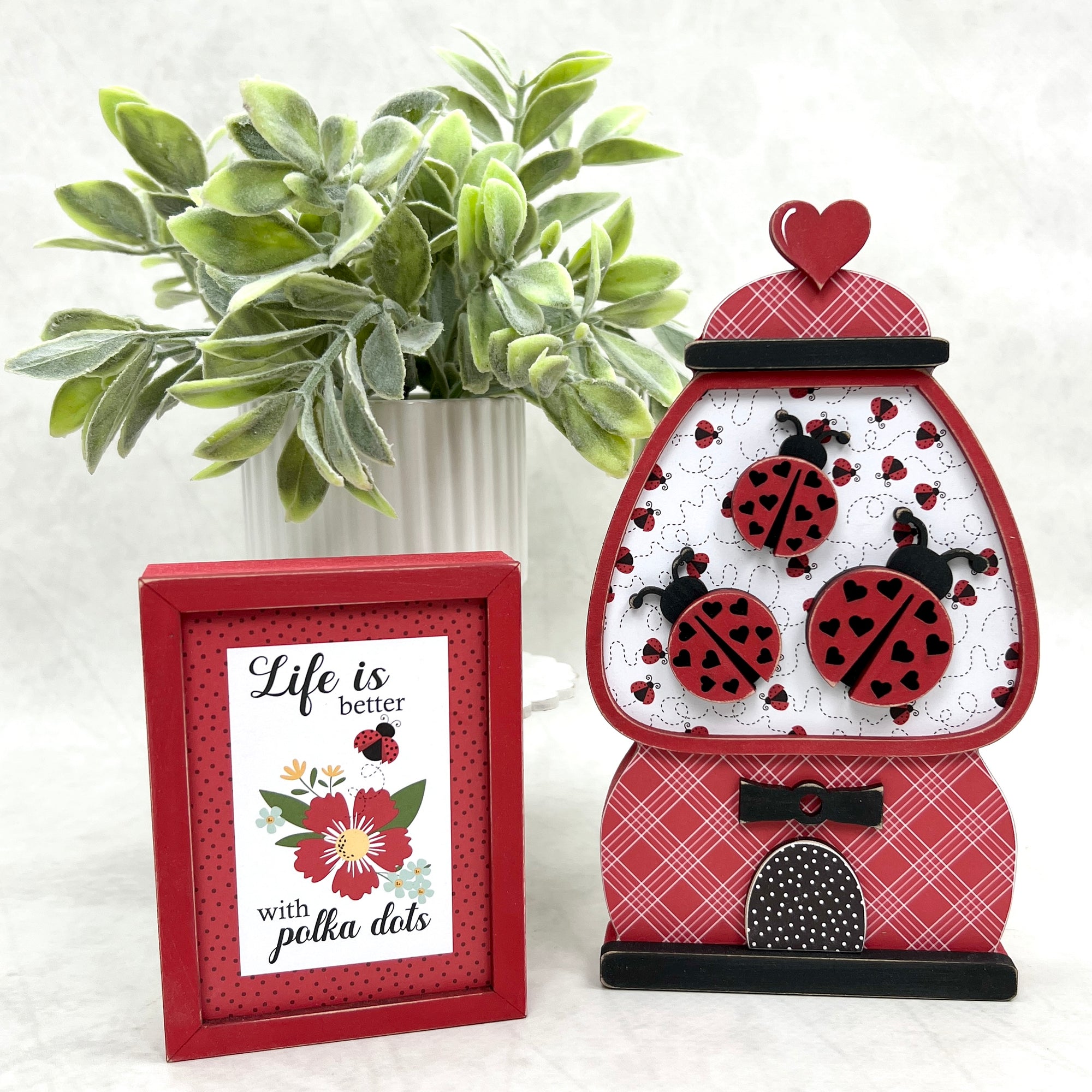Red gumball machine with ladybugs inside with a block sign that says life is better with polka dots. DIY wood decor craft kit