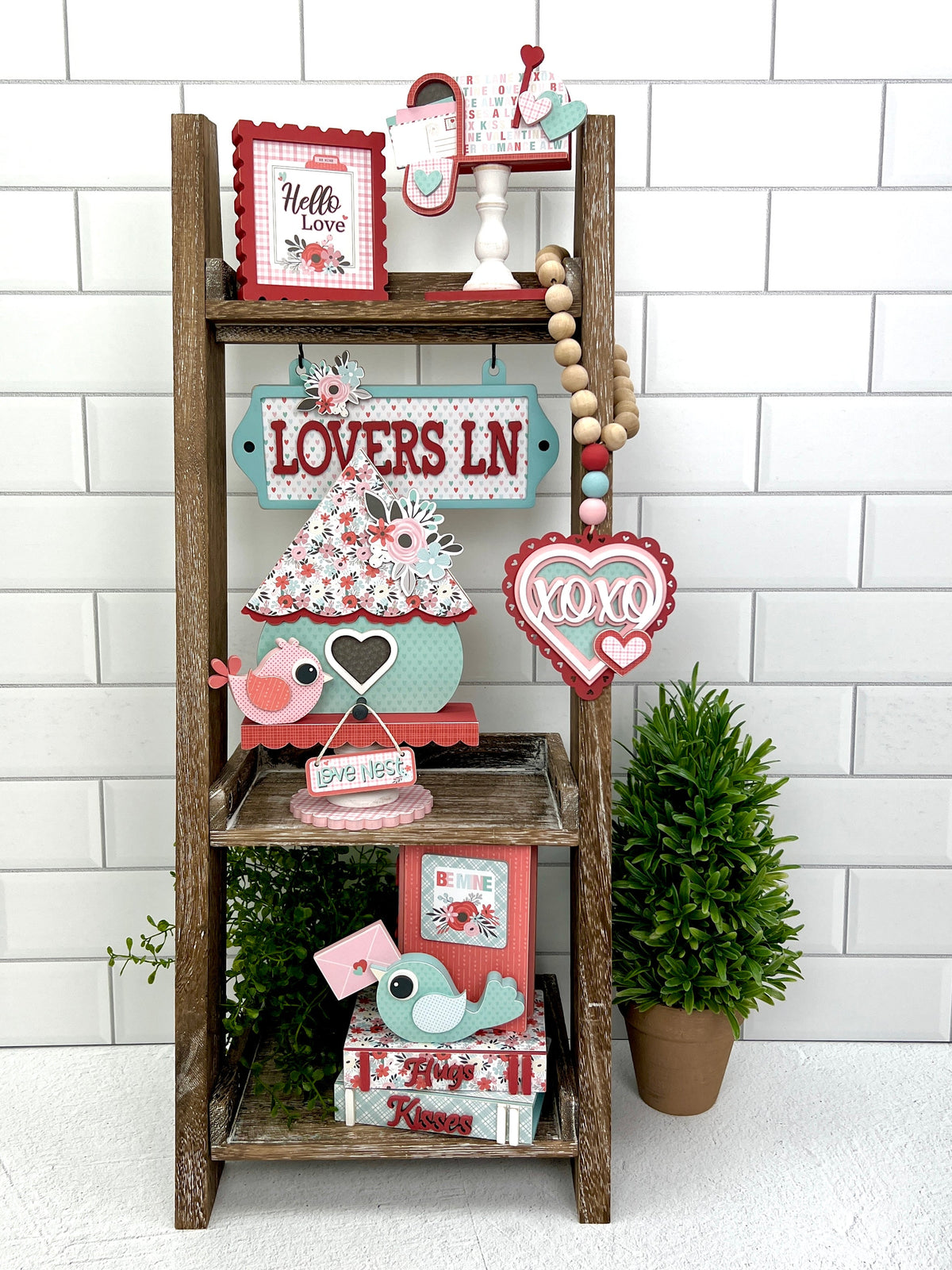 Leaning ladder with Valentine birdhouse themed wood decorations in red, pink, and blue
