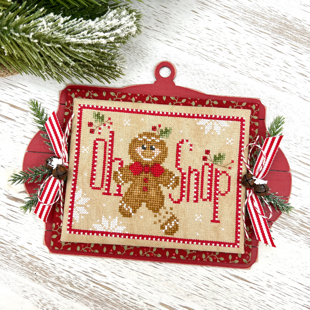Oh Snap cross stitch gingerbread man in a red bow tie on a red shiplap ornament board