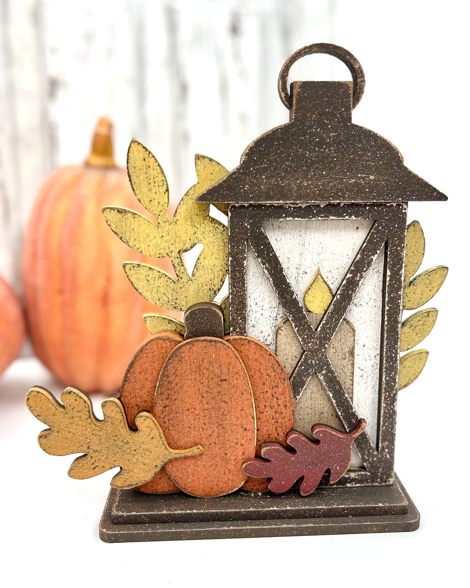 Rustic fall lantern wood display with layered pumpkin, candle, and leaf accents; painted in distressed autumn colors with space to attach a small cross stitch motif.