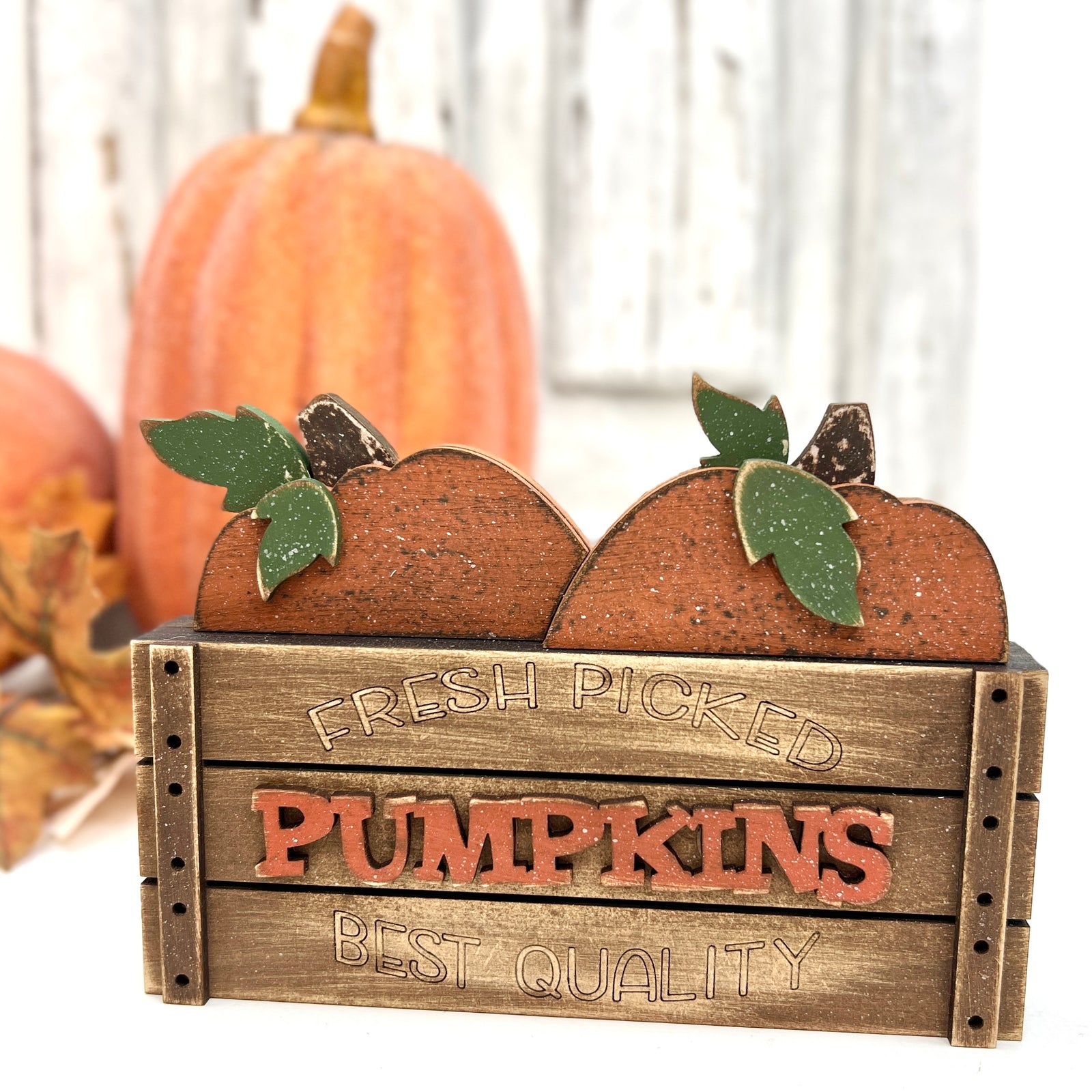 Rustic “Fresh Picked Pumpkins” wood crate décor with layered orange pumpkins and green leaves, painted in distressed farmhouse colors for a cozy fall display.