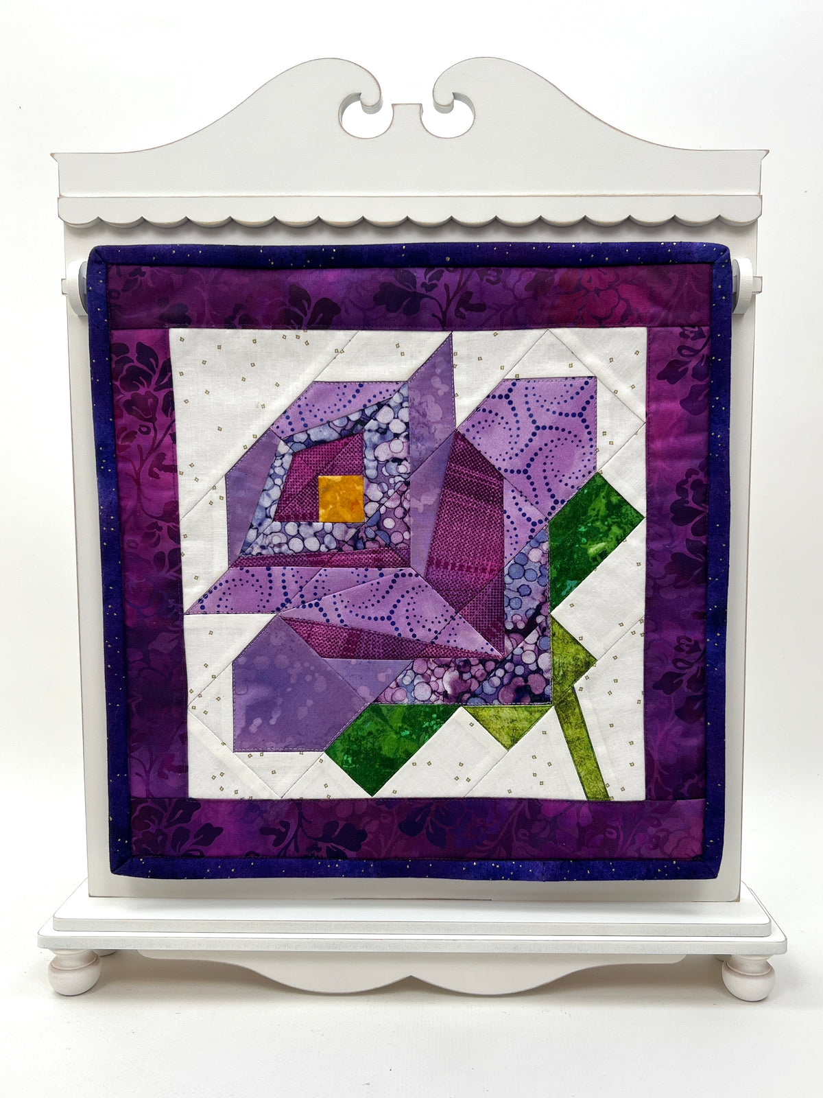 Quilted square with geometric pattern on a white stand