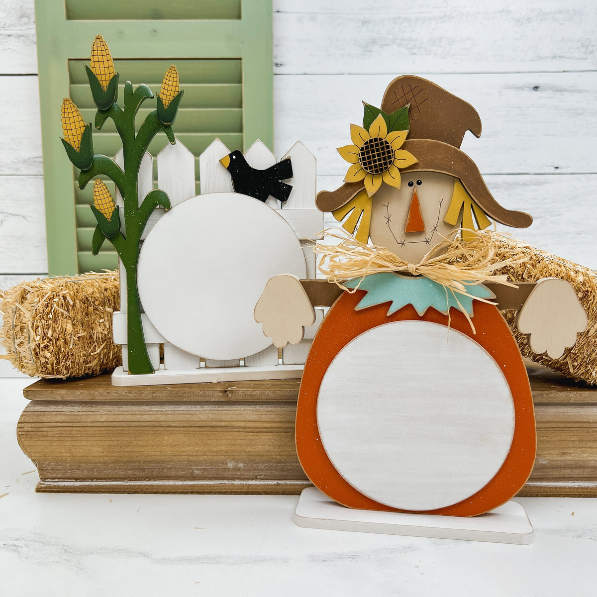 Wood scarecrow and a picket fence with a cornstalk cross stitch displays.