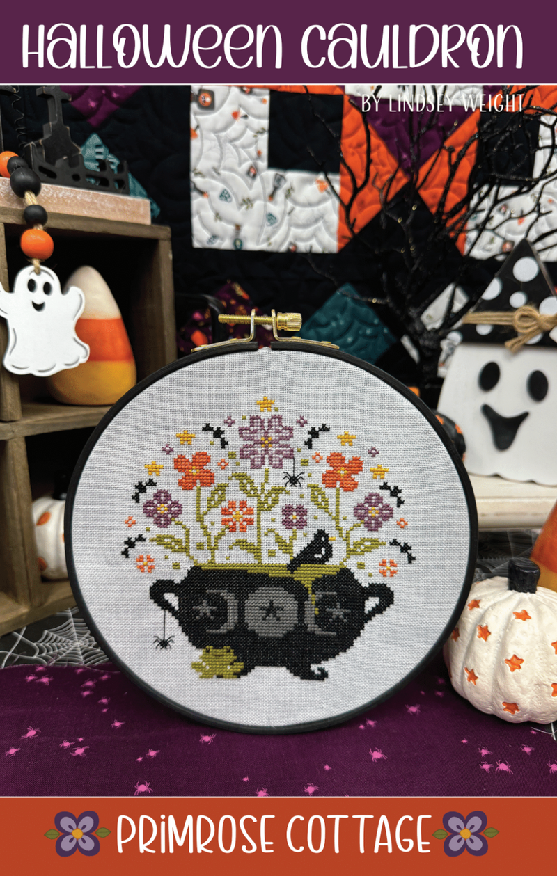 Halloween-themed cross-stitch design featuring a cauldron with flowers, surrounded by Halloween decorations.