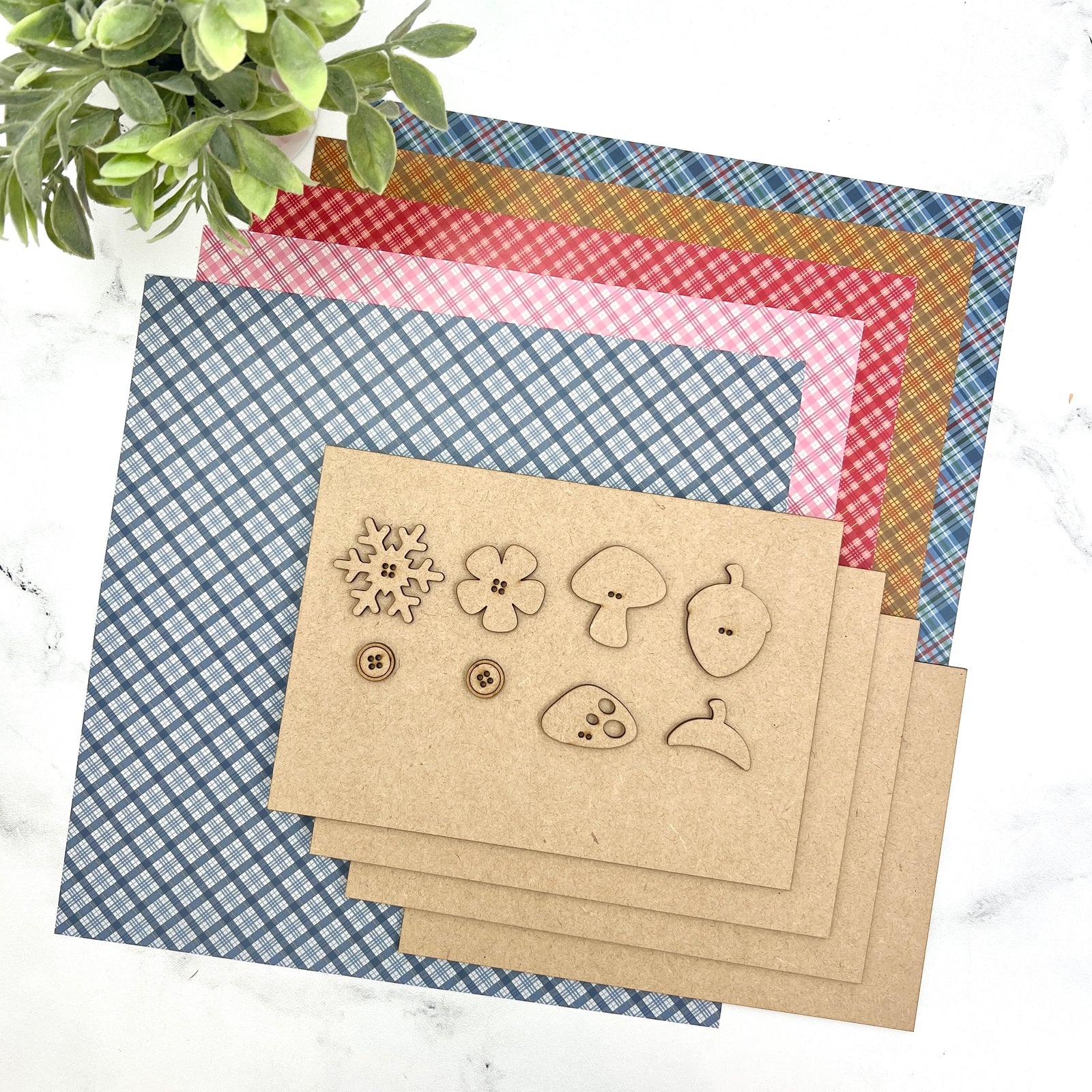 Seasonal Samplings backer boards with seasonal charms including an acorn, snowflake, mushroom, and flower for interchangeable cross stitch display styling.