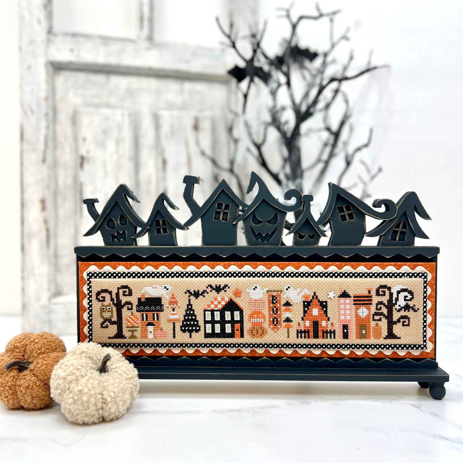 Decorative Halloween scene with black houses and pumpkins on a white background with Halloween Tiny Town cross stitch by Heart in Hand.