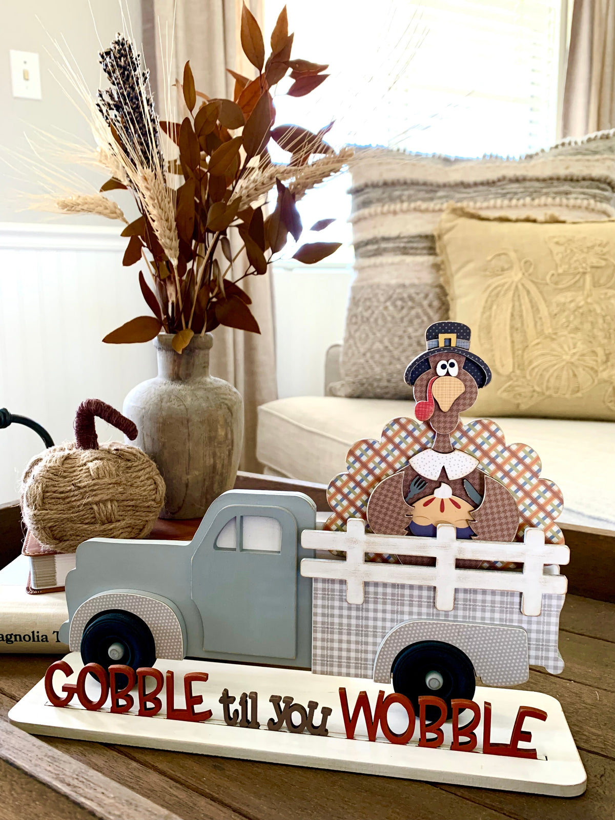 Interchangeable truck with a turkey insert and gobble til you wobble phrase sitting on a coffee table. Interchageable wood truck with changing seasonal inserts.
