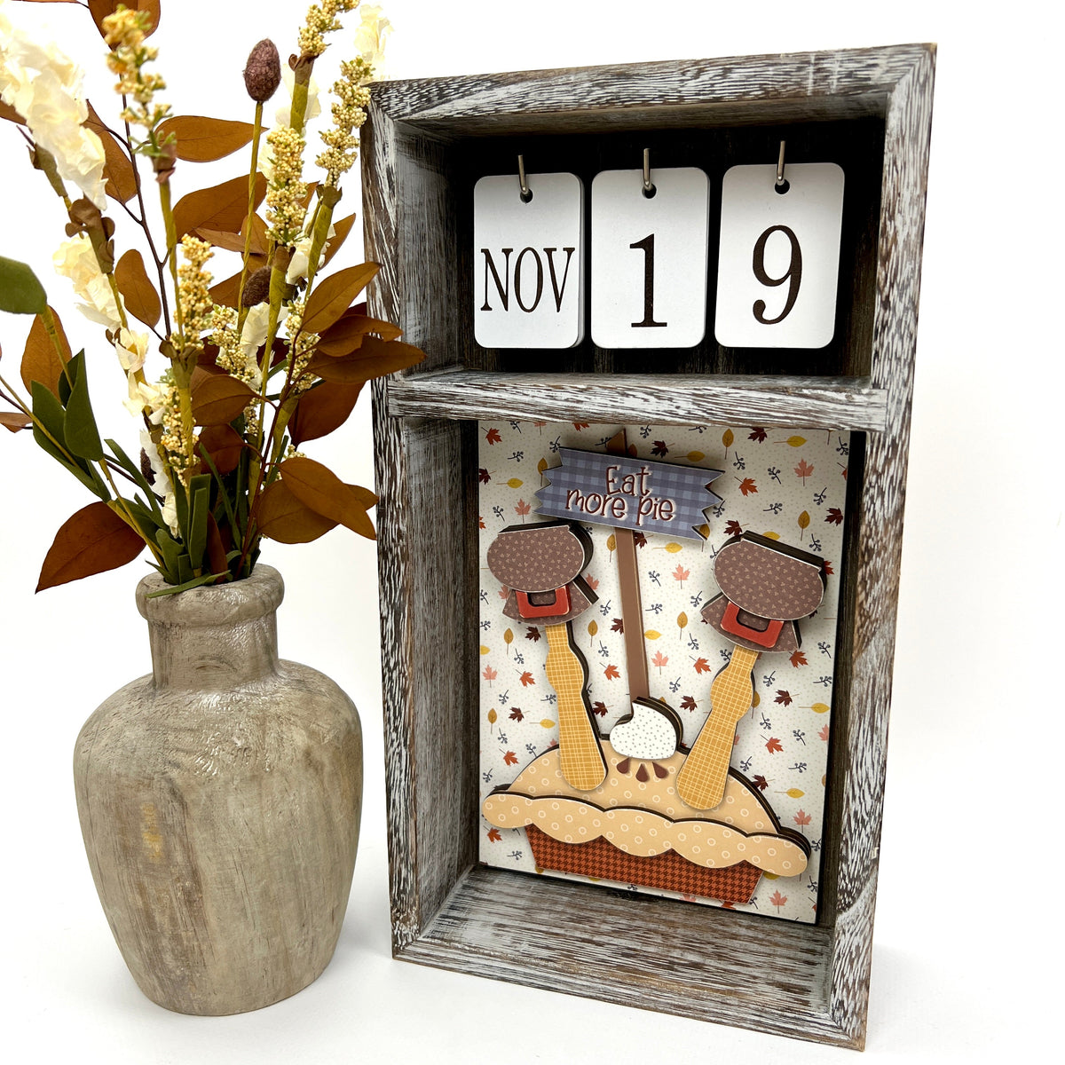 Turkey with legs coming out of a pie wood decoration displayed in a calendar box.