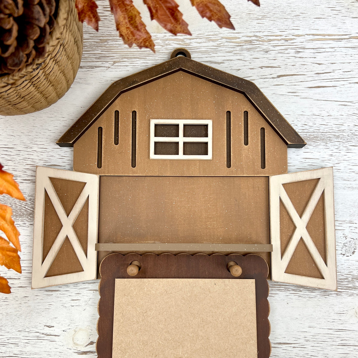 Barn-shaped DIY wood cross stitch display with shelf, open doors, and hanging pegs