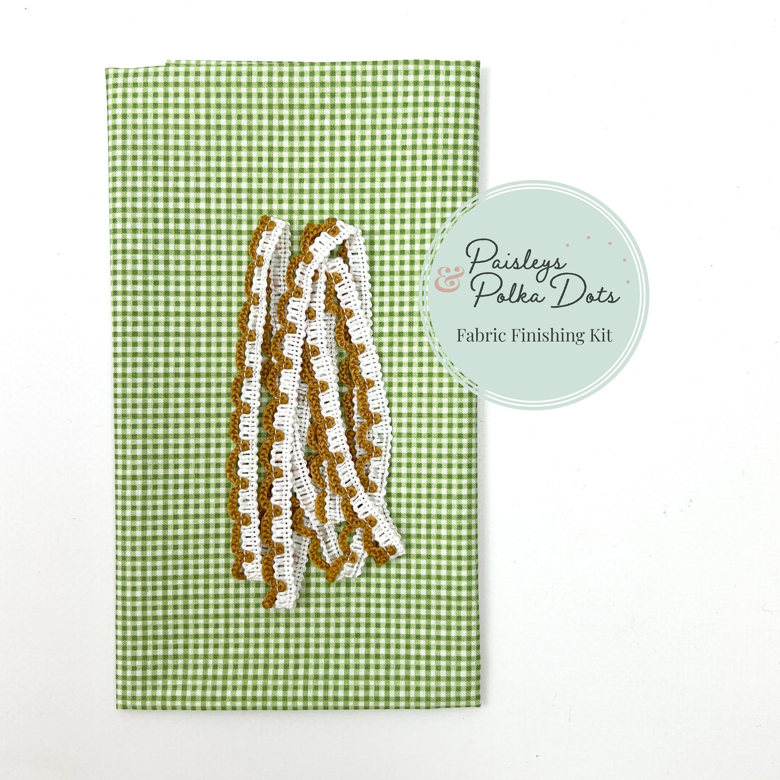 Fabric finishing kit with lace trim on a green gingham checkered background.