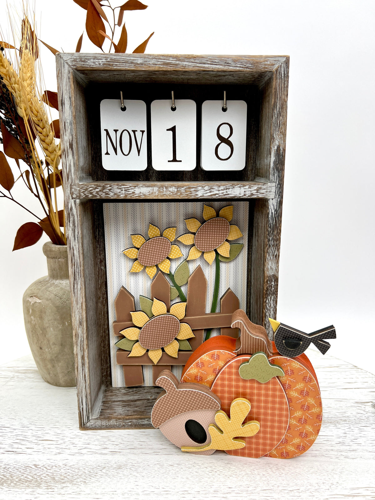seasonal wood calendar box with changing inserts shown with fall pumpkin, sumnflowers and picket fence