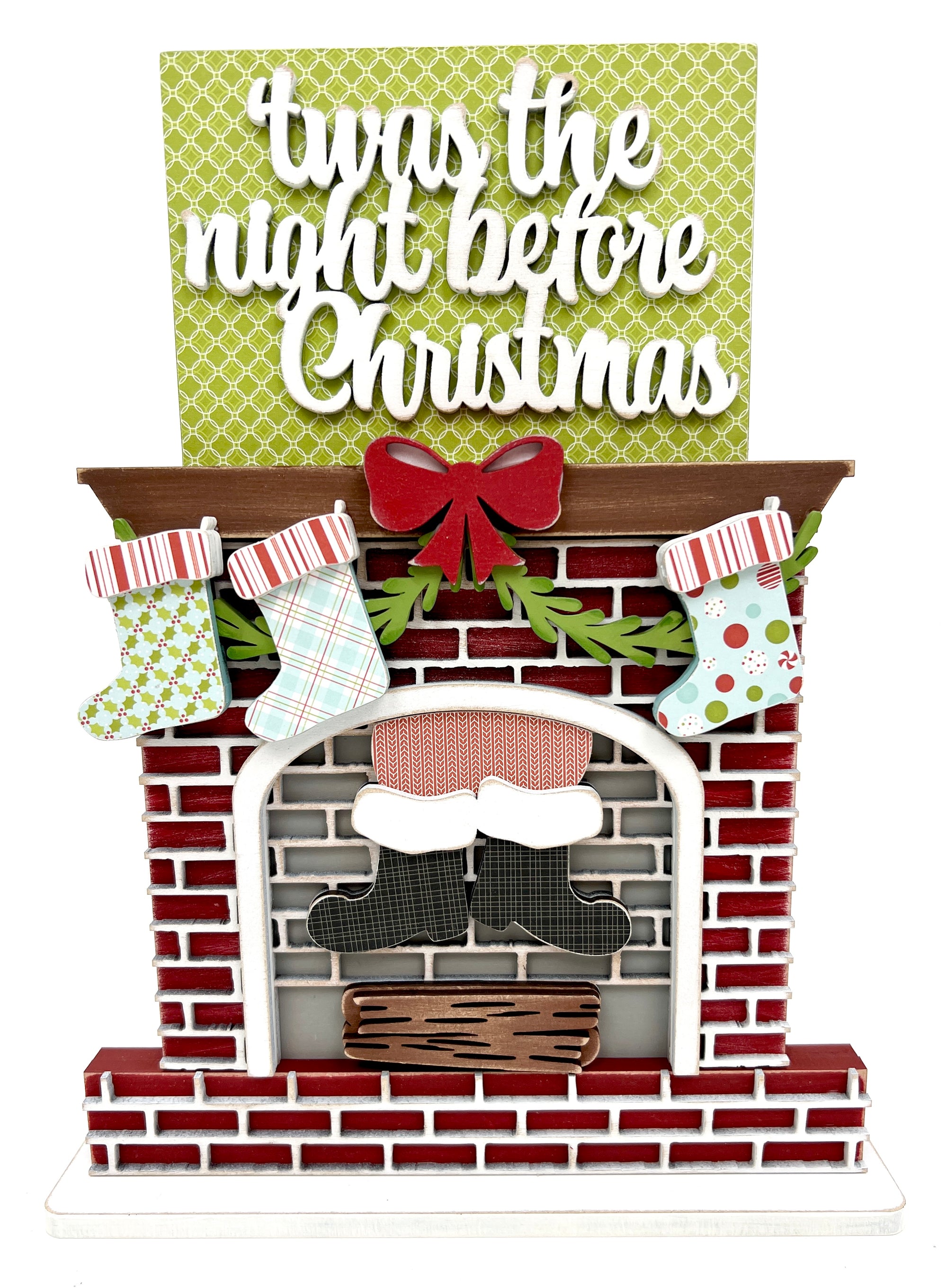 Wood craft kit that is a Christmas fireplace with Santa coming down the chimney, stockings hanging from a mantel and a title that says Twas the night before Christmas