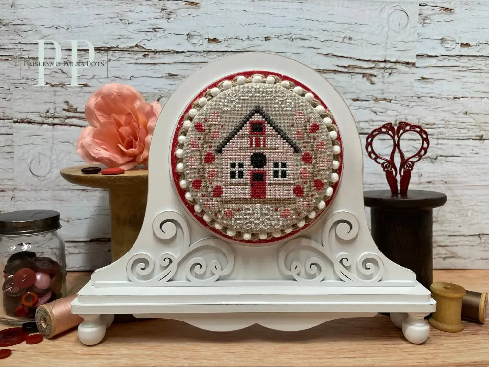 Bird house cross stitch by Erin Elizabeth Designs shown on a white wood cross stitch display with a fleur design on the front.