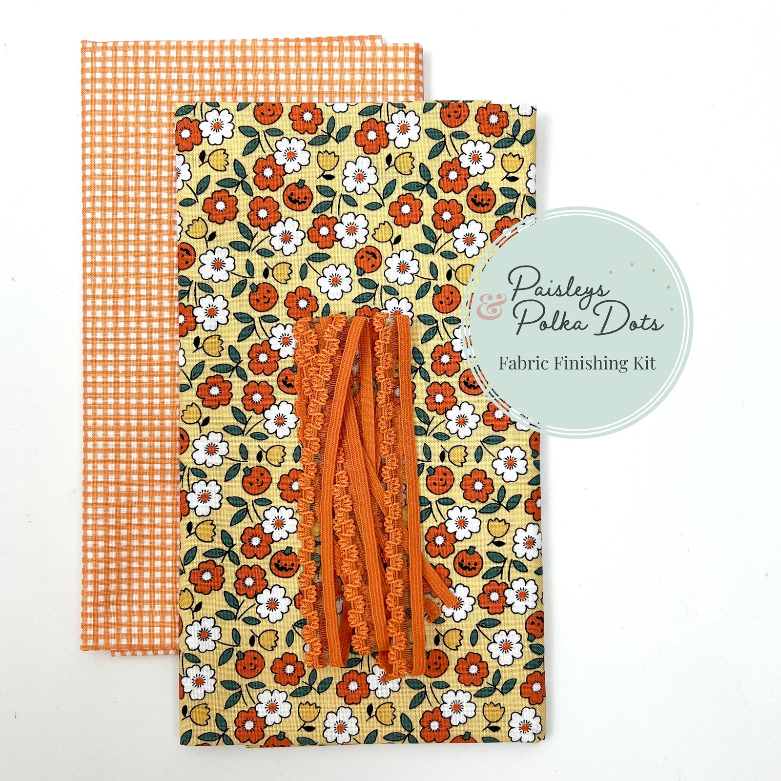 Fabric finishing kit with floral and checkered patterns featuring happy jack-o-lanterns with white, yellow and orange fall flowers