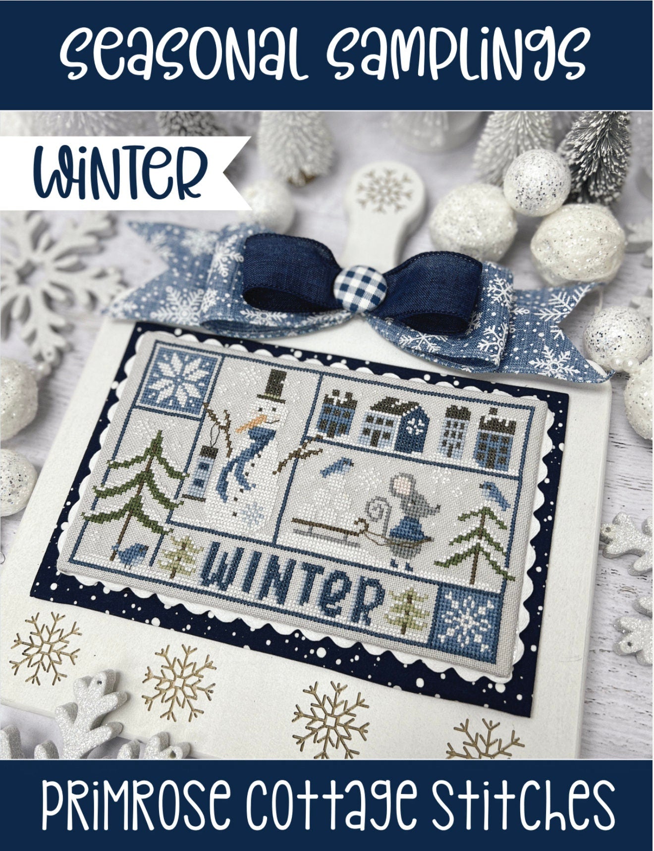 Cross-stitched design with winter-themed elements on a card, featuring snowflakes and a bow, with 'Primrose Cottage Stitches' branding.