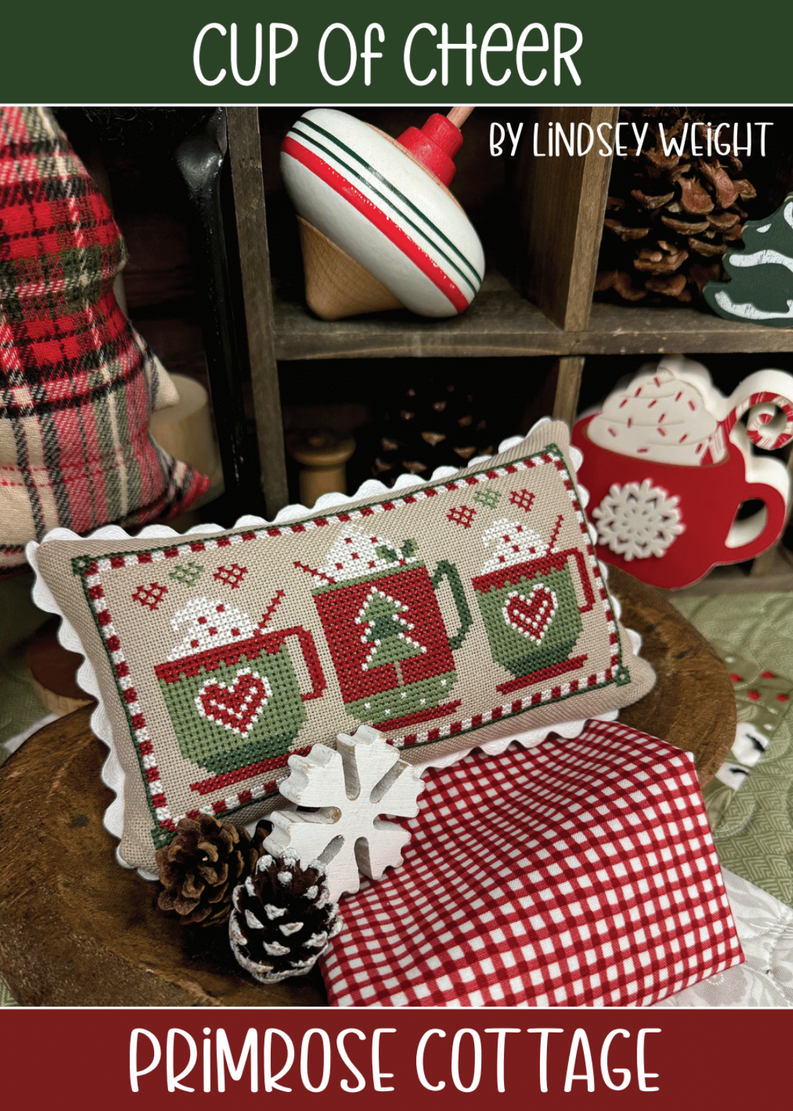 Decorative pillow with cross-stitch design of three mugs of Christmas Cheer sprinkled with whipped cream and hot cocoa cheer
