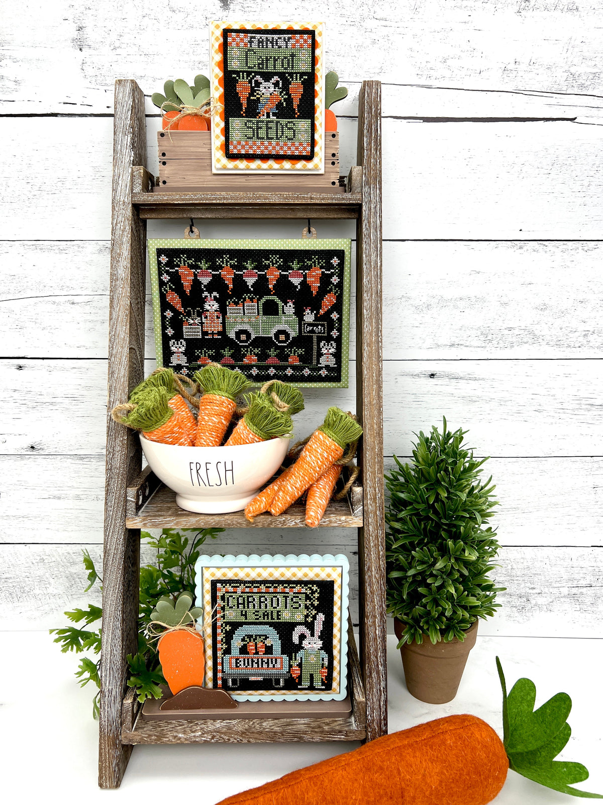 Wood ladder shelf with finished easter themed cross stitch pieces from Stitching with the housewives