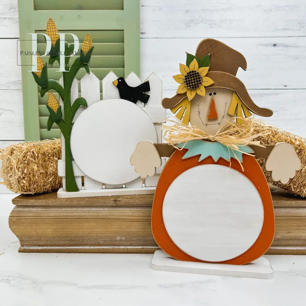 Wood scarecrow and a picket fence with a cornstalk cross stitch displays.