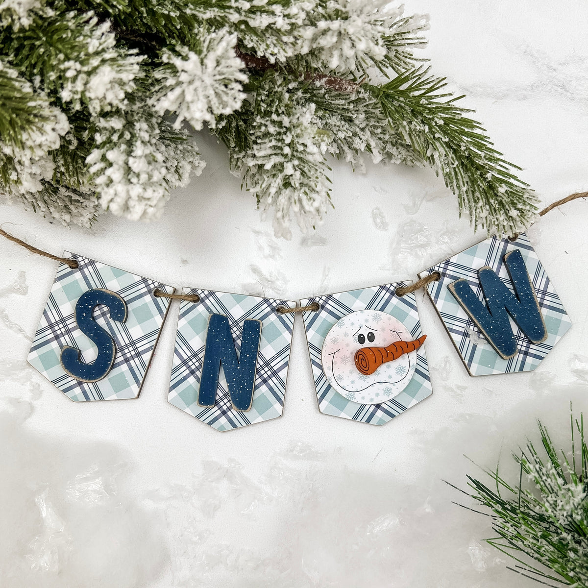 Decorative banner with snowman and plaid design on a snowy background