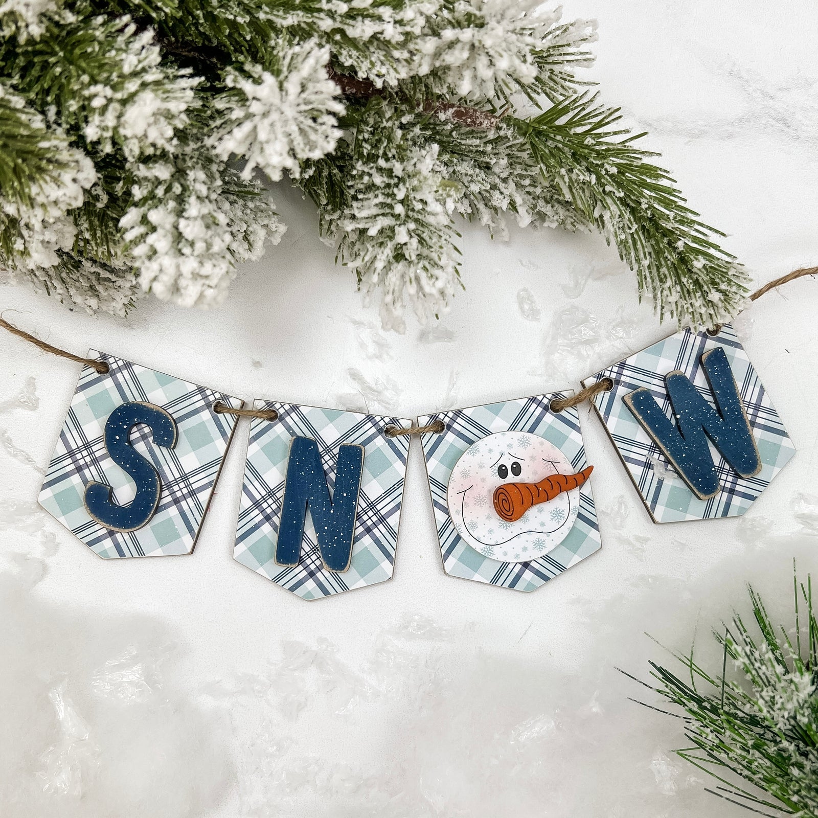 Decorative banner with snowman and plaid design on a snowy background