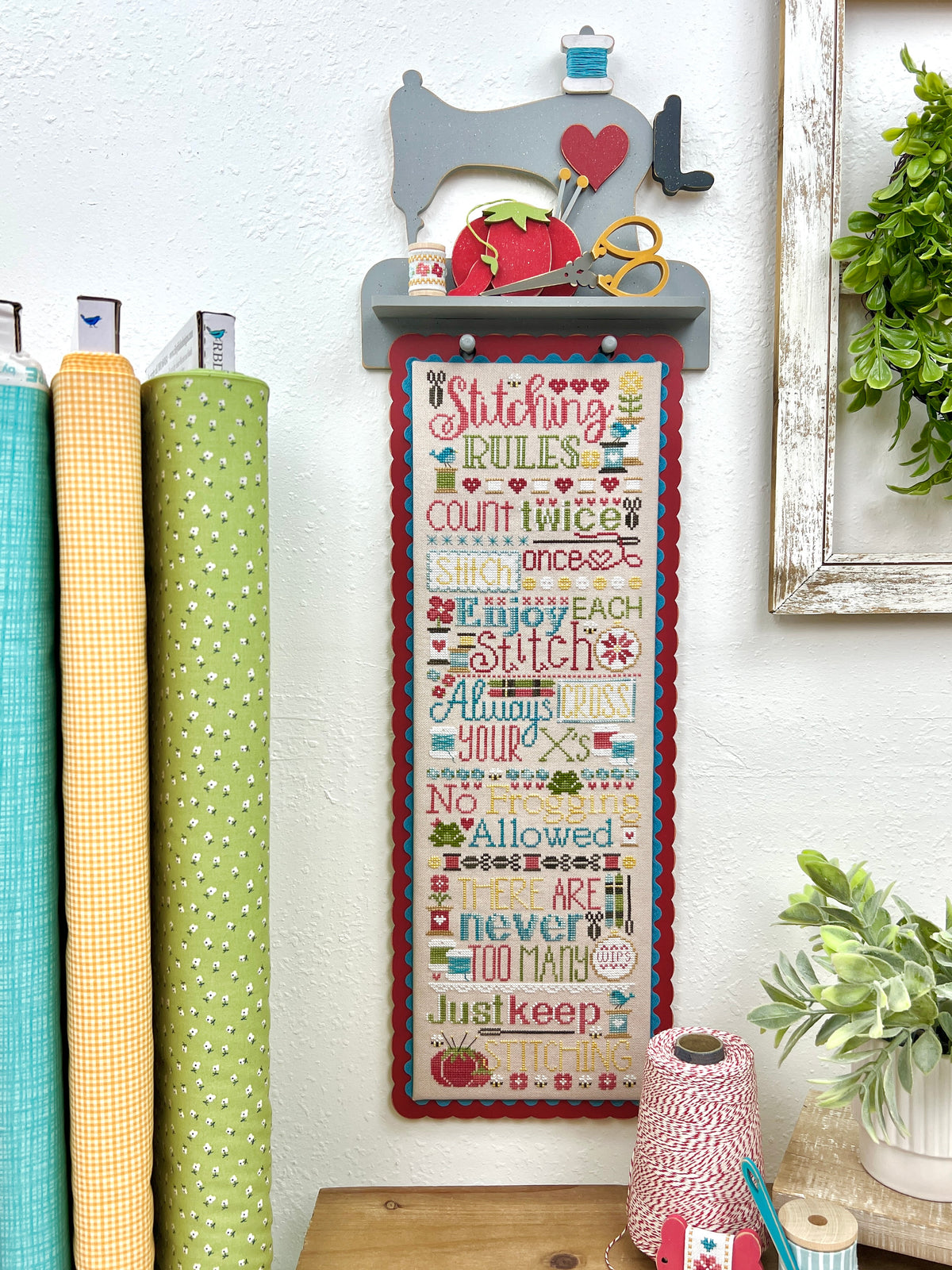 Primrose Cottage Stitching Rules cross stitch displayed on a sewing machine wood wall shelf