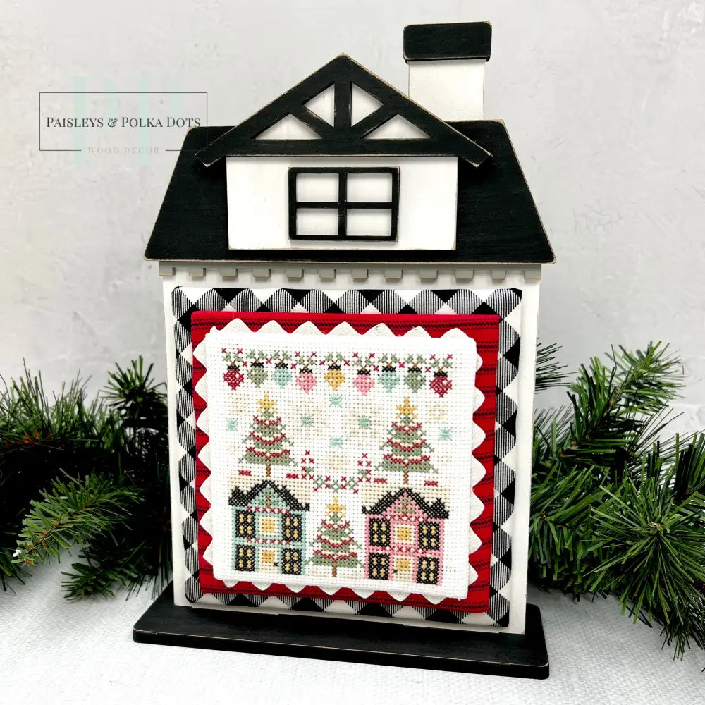 Stitching with the Housewives Cith Christmas Cross Stitch shown on black and white wood city house 